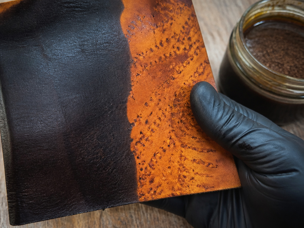 Close-up of leather showing the chemical black dye effect of vinegaroon versus oil-stained areas.